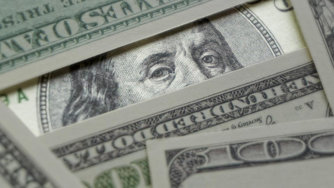 Ben Franklin peeking out from between $100 bills