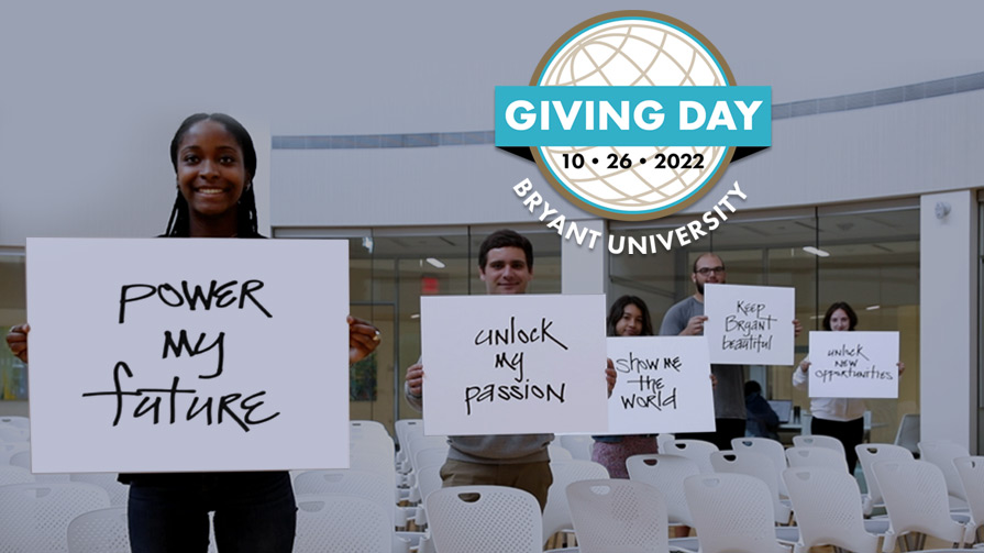 News Image - Students holding Bryant Giving Day signs in the Academic Innovation Center forum.