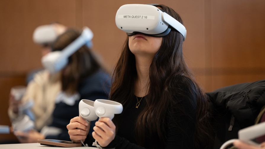 Woman wears virtual reality headset and while holding two handles.