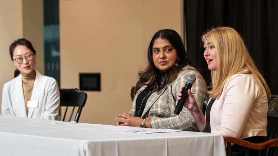 Bryant's Kacy Kim (left) interviews two panelists during the Analytics Without Borders conference.