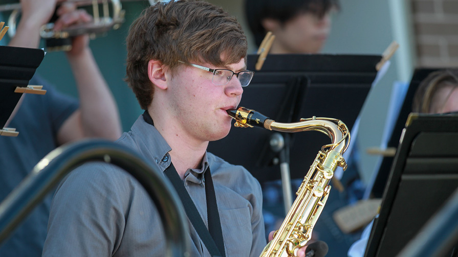Student sitting and playing saxophone.