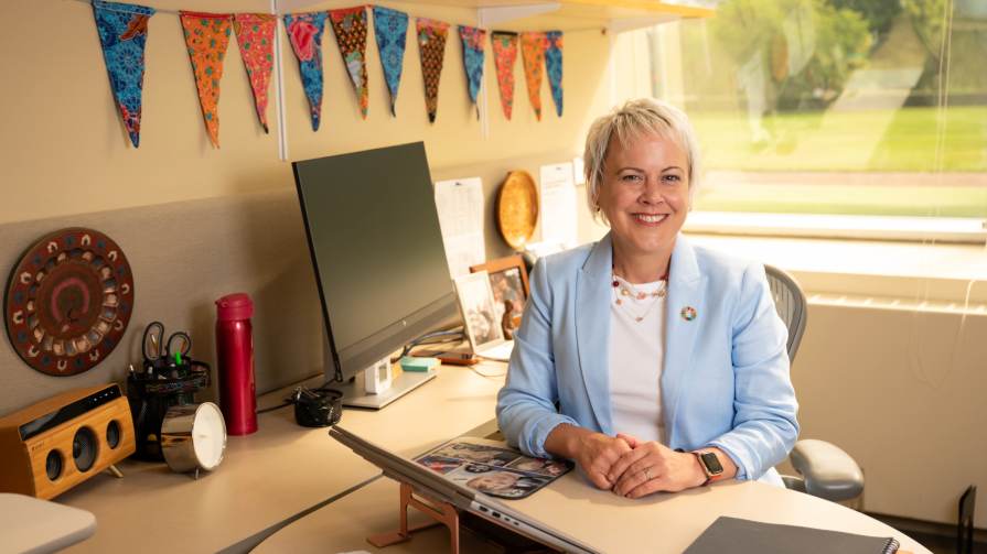 Denise Horn sits at office desk.