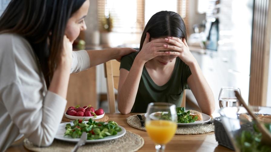 Mom and daughter at dinner table.