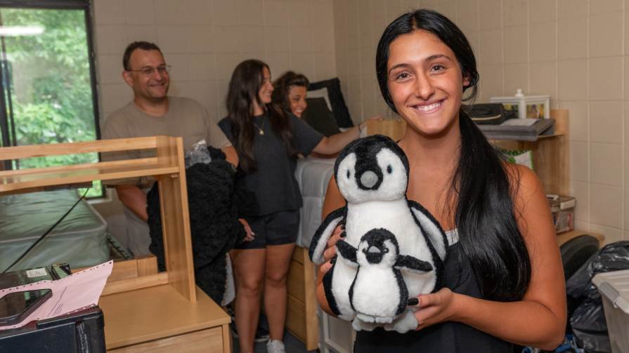 Nadia Del Sonno holds a penguin stuffed animal in her dorm room.