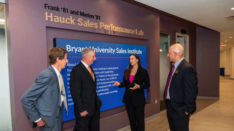 Frank Hauck ’81 discusses the future with Professor of Marketing and Director of the Bryant Sales Program Stefanie Boyer, Ph.D., Bryant University President Ross Gittell, Ph.D., and Todd Alessandri, Ph.D., dean of the College of Business in front of the Frank ’81 and Marion ’81 Hauck Sales Performance Lab at Bryant's BELC Lead Donor Recognition Ceremony