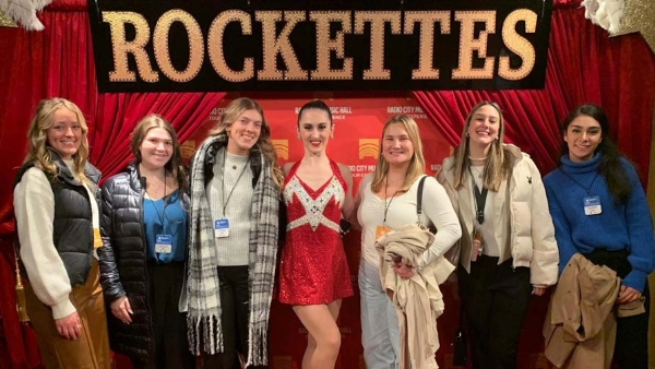 Six students pose with a Rockette at Radio City Music Hall.