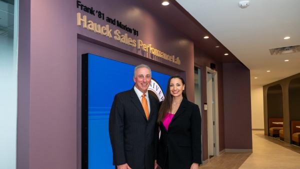 Frank Hauck ’81 poses with Professor of Marketing and Director of the Bryant Sales Program Stefanie Boyer, Ph.D., in front of the Frank ’81 and Marion ’81 Hauck Sales Performance Lab, a 5,000-squ