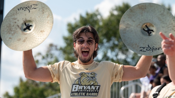 Recent alum James Tiner ’24 plays the cymbals with the Bryant University Athletic Bands.  