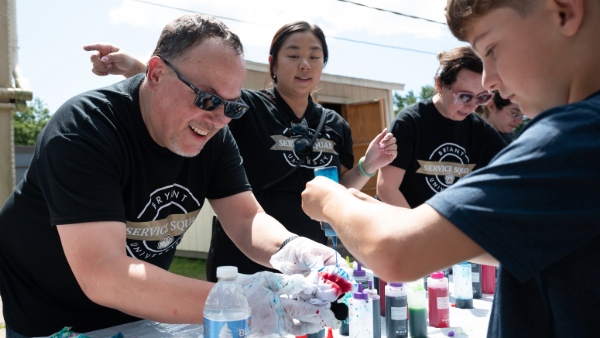 Bryant employees help students create tie die shirts at the Smithfield YMCA