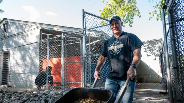 Todd Alessandri, Bryant University's dean of the College of Business, pushes a wheelbarrow of mulch to help with landscaping efforts at the Hotel for Homeless Dogs.