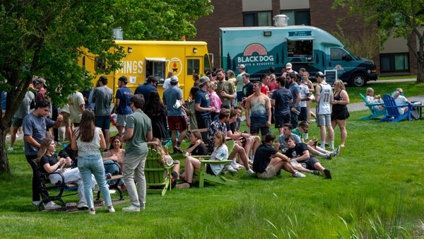Food trucks by pond with students.