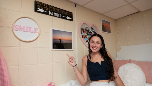 Girl points to sunrise photo on bedroom wall.